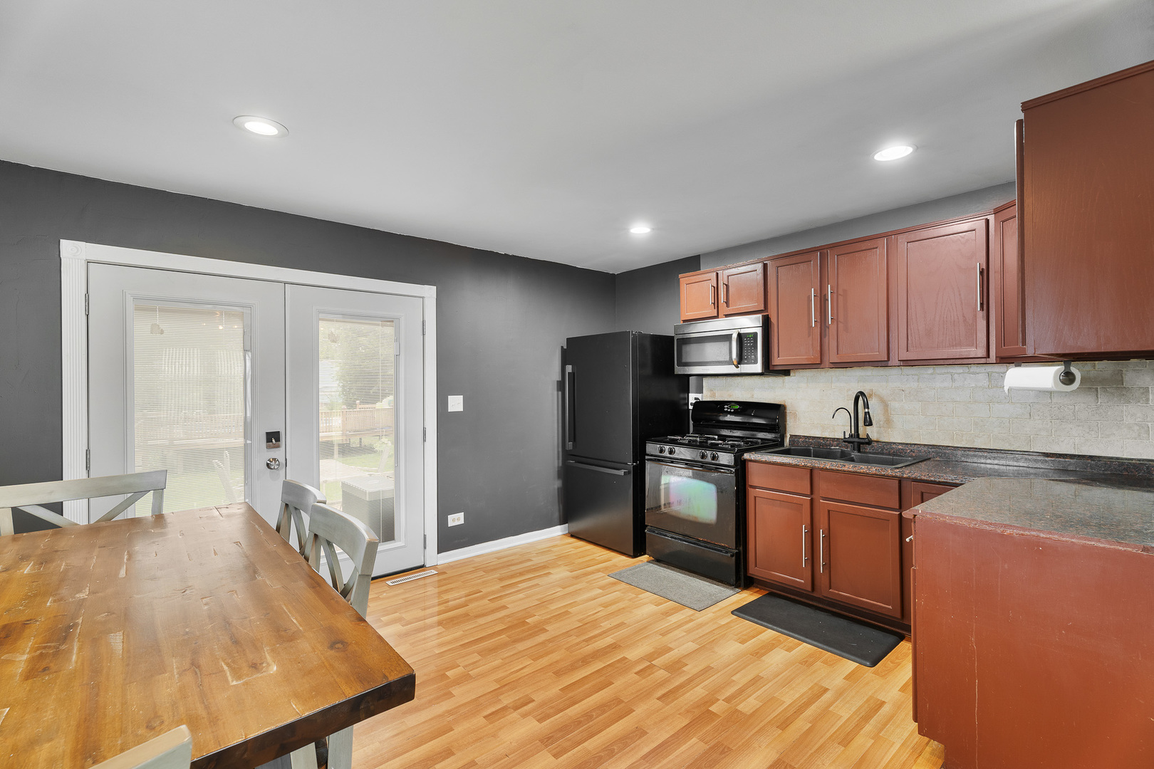 302 South Oltendorf Road Streamwood, IL 60107 - Photo 7 of 19 a large kitchen with stainless steel appliances granite countertop a refrigerator a sink dishwasher a stove with wooden cabinets and floor