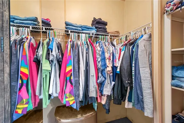 a view of walk in closet with clothes and shoes