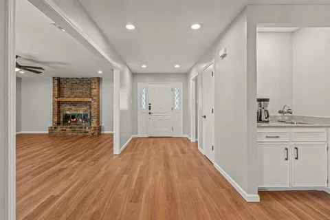 a view of a hallway with wooden floor and a bathroom