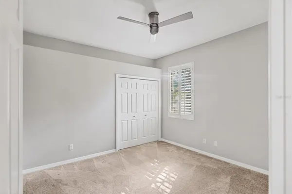 an empty room with windows and fan