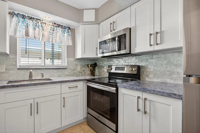 a kitchen with granite countertop white cabinets white stainless steel appliances and a sink