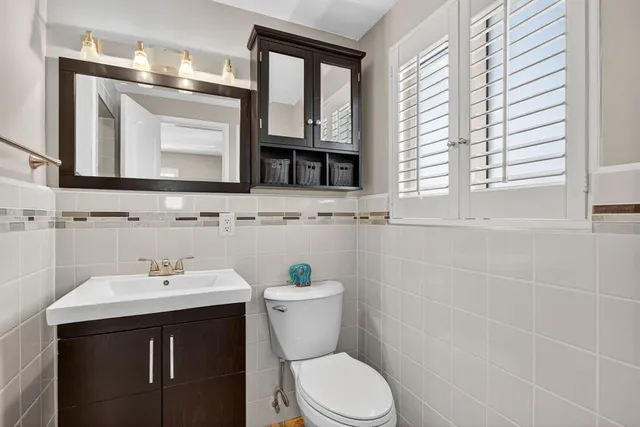 a bathroom with a toilet a sink a mirror and a window