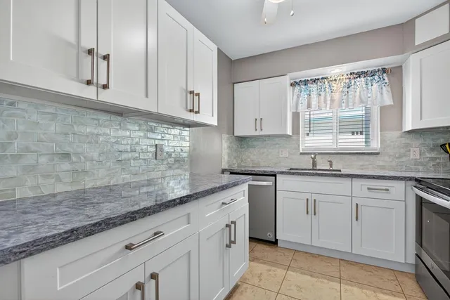 a kitchen with granite countertop white cabinets white appliances with a sink and dishwasher
