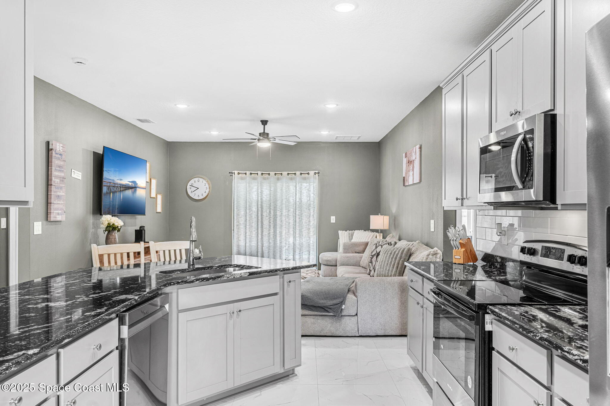 1125 Satin Road Palm Bay, FL 32908 - Photo 7 of 26 a kitchen with stainless steel appliances granite countertop a sink stove oven and white cabinets