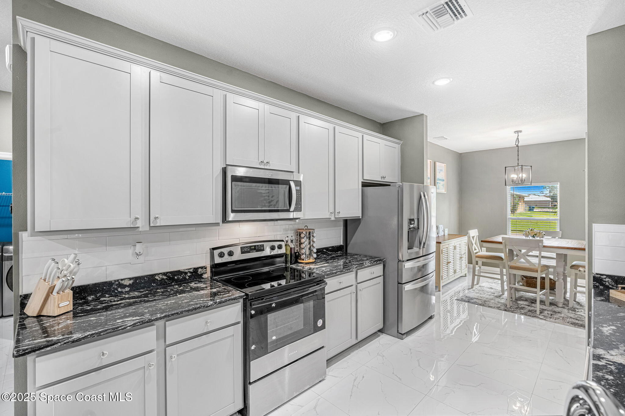 1125 Satin Road Palm Bay, FL 32908 - Photo 9 of 26 a kitchen with stainless steel appliances granite countertop a stove a sink and a refrigerator