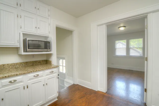 a kitchen with granite countertop white cabinets and stainless steel appliances