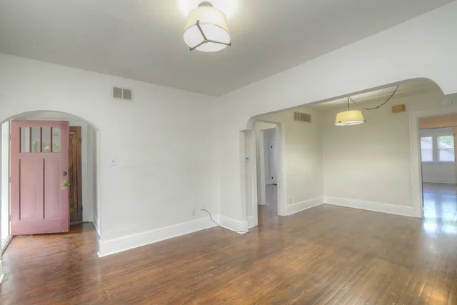 an empty room with wooden floor and mirror