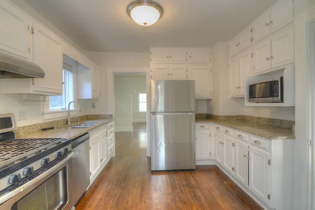 a kitchen with granite countertop a refrigerator stove top oven and sink