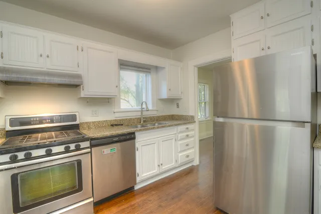 a kitchen with stainless steel appliances granite countertop a refrigerator a stove a sink and white cabinets