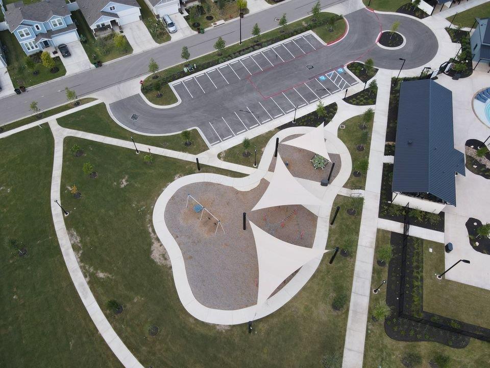 156 Huckleberry Lane Elgin, TX 78621 - Photo 11 of 16 An aerial perspective reveals a vibrant community park with extensive walking paths and a modern playground.