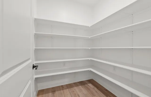 an empty room with wooden floor chandelier fan and windows