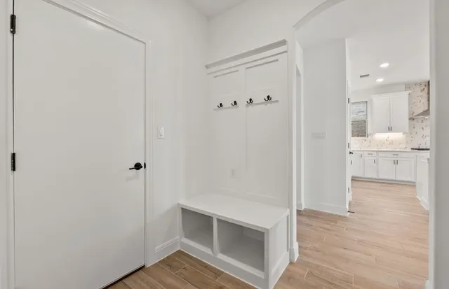 a view of an empty room with wooden floor and a ceiling fan