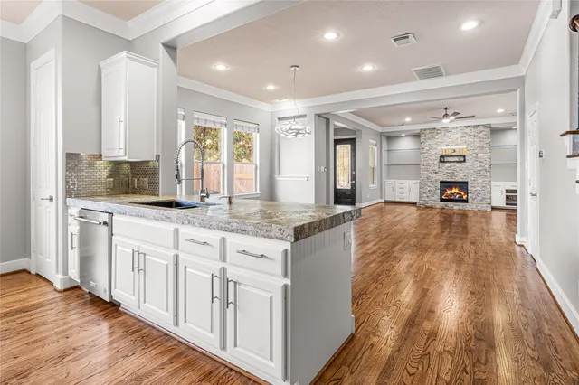 a large kitchen with kitchen island granite countertop a large window a oven and white cabinets
