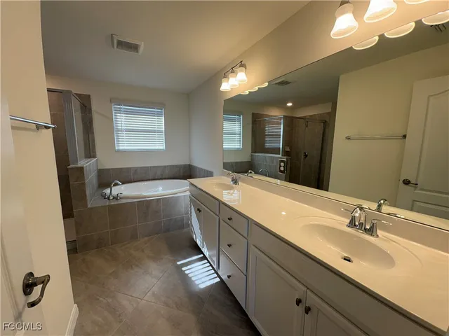 a spacious bathroom with a bathtub sink and mirror