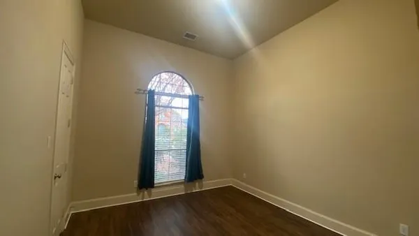 an empty room with wooden floor and a ceiling fan