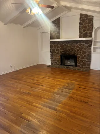 a view of empty room with wooden floor and fireplace