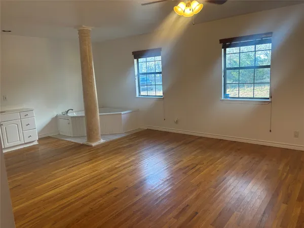 an empty room with wooden floor and windows
