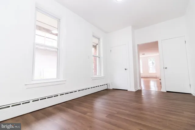 an empty room with wooden floor and windows