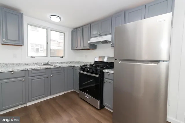 a kitchen with granite countertop a refrigerator sink and cabinets