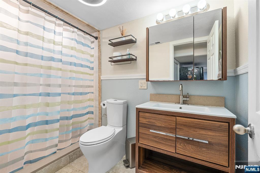 71 Wingra Avenue Rutherford, NJ 07070 - Photo 13 of 20 a bathroom with a sink a toilet and shower curtain