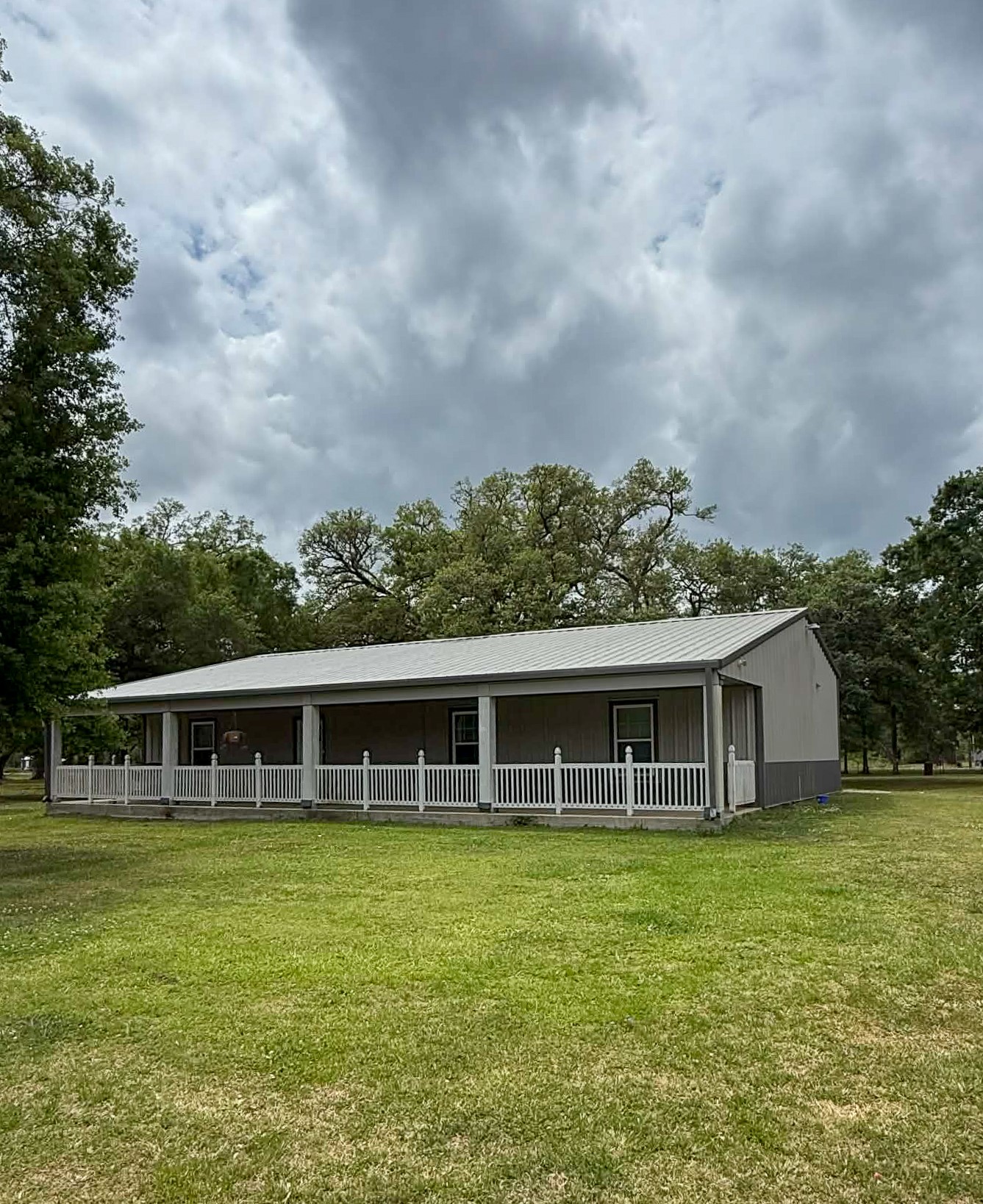 107 County Road 409 Sweeny, TX 77480 - Photo 1 of 20 This charming single-story home features a spacious front porch and is set on a lush, expansive lawn surrounded by mature trees, offering a serene and inviting atmosphere.
