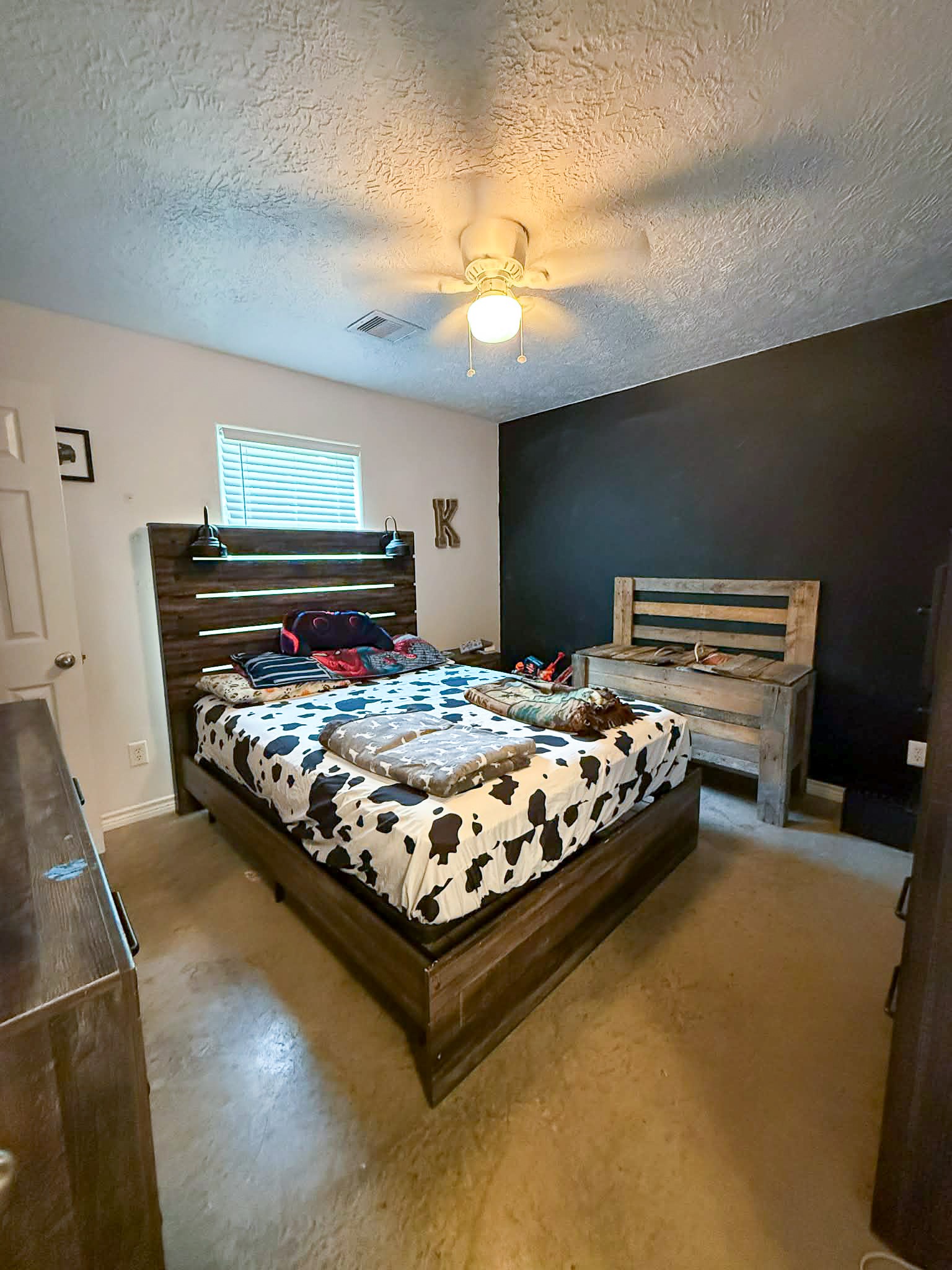 107 County Road 409 Sweeny, TX 77480 - Photo 14 of 20 Cozy bedroom featuring a dark (chalkboard) accent wall. The space is well-lit with natural light from a window.
