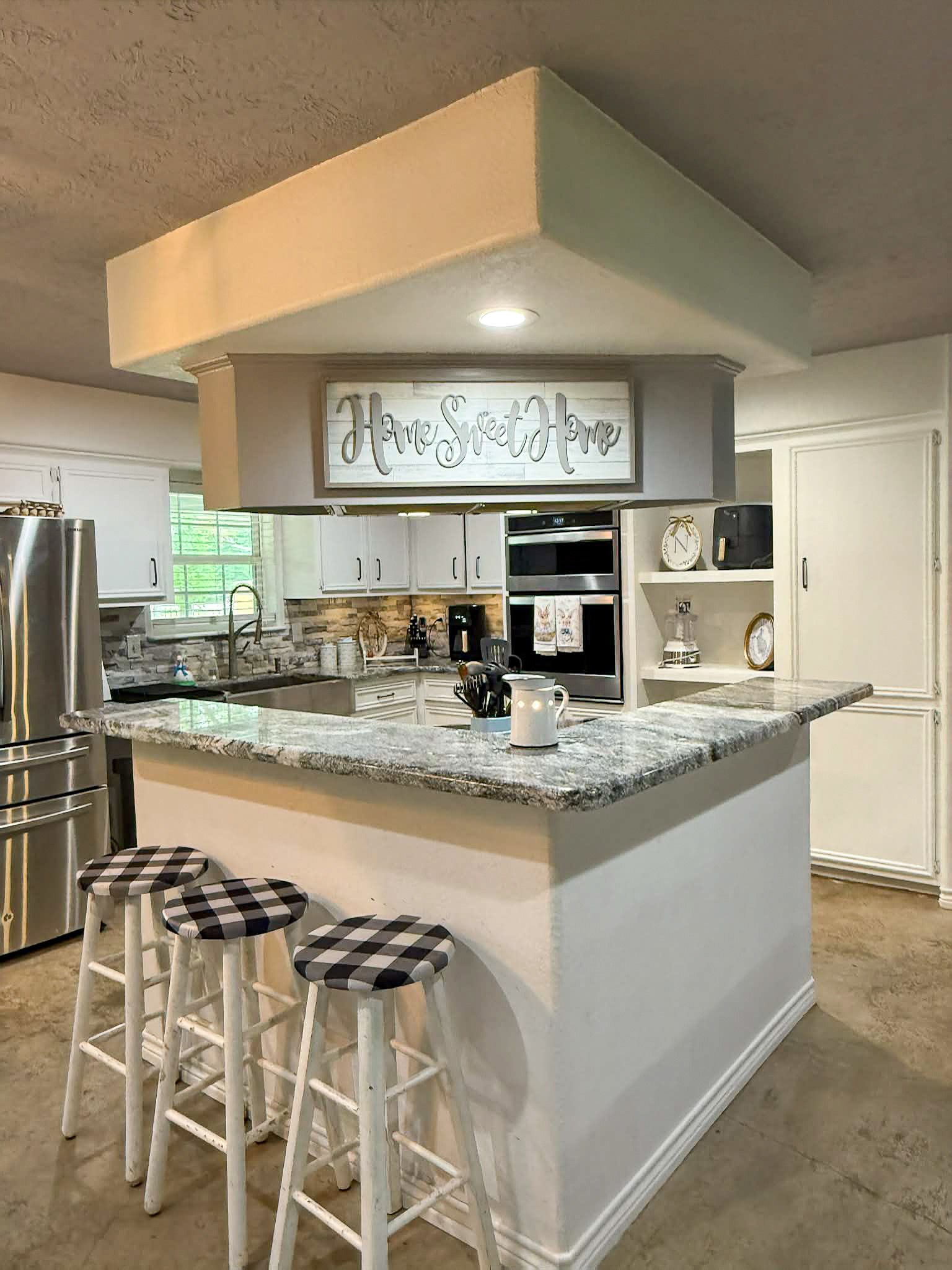 107 County Road 409 Sweeny, TX 77480 - Photo 5 of 20 This kitchen features a cozy breakfast bar, quartz countertops, and modern stainless steel appliances.