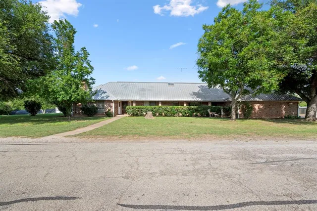 a view of a house with a big yard and large trees