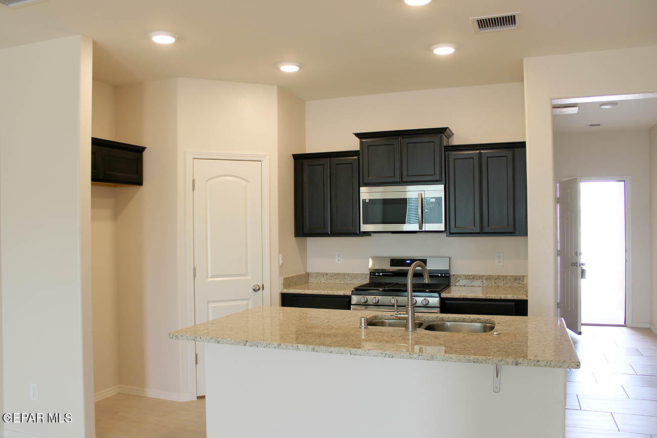 a kitchen with stainless steel appliances granite countertop a refrigerator and a stove top oven