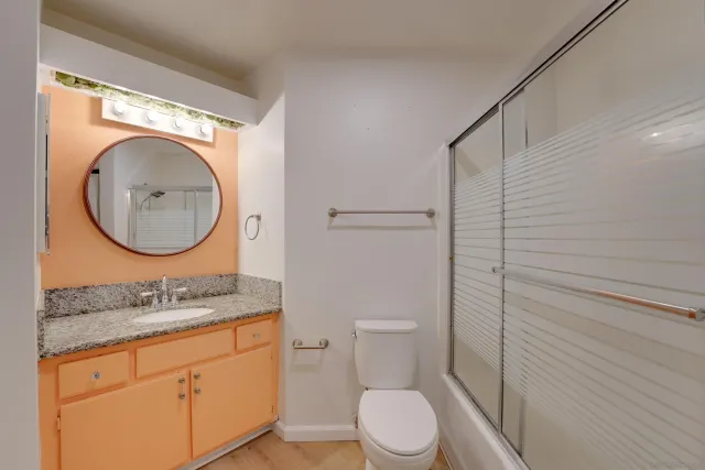 a bathroom with a granite countertop toilet sink and mirror
