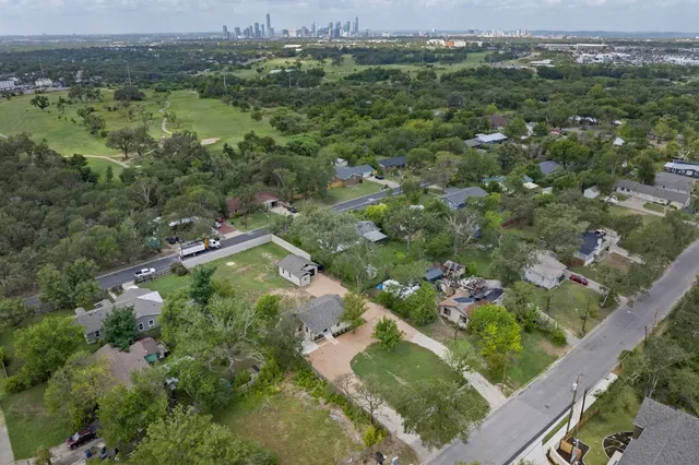 an aerial view of residential houses with outdoor space and trees