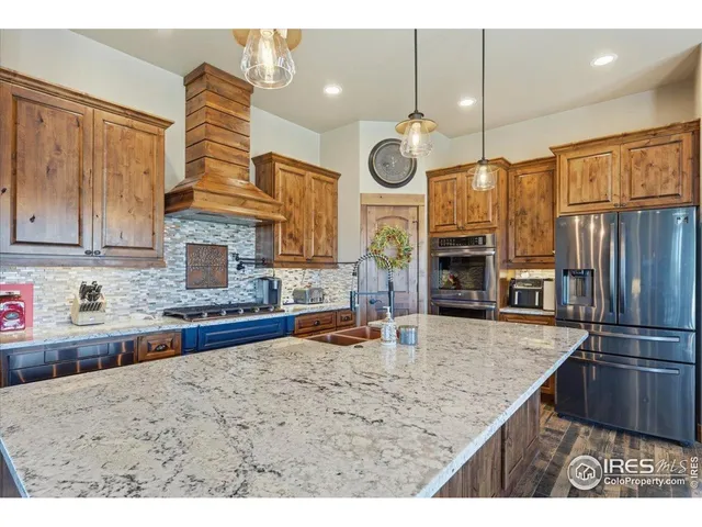 a kitchen with stainless steel appliances granite countertop a sink a stove and a refrigerator
