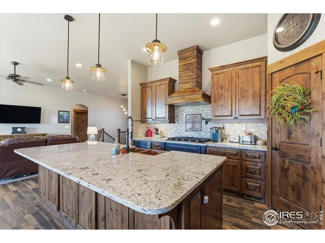 a kitchen with kitchen island granite countertop a table a stove a sink dishwasher and cabinets with wooden floor