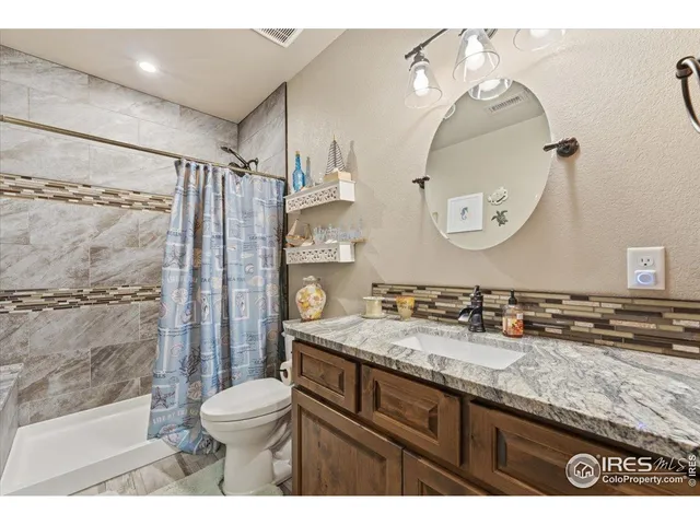 a bathroom with a granite countertop sink mirror vanity and toilet