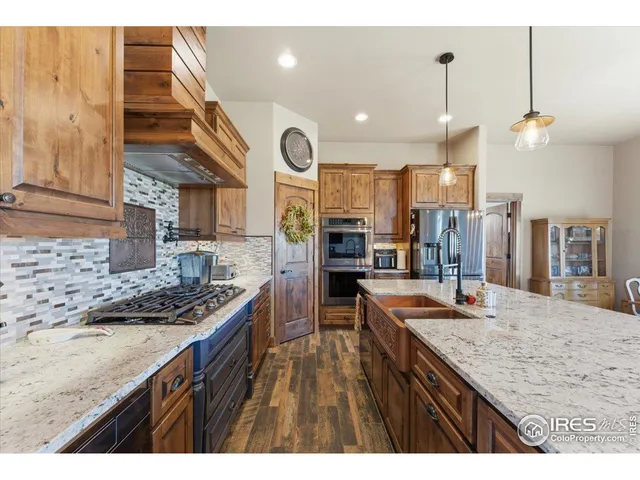 a kitchen with stainless steel appliances granite countertop a sink a stove and a wooden floors