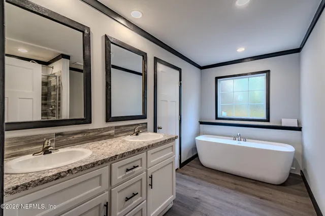 a spacious bathroom with a double vanity sink a mirror and a bathtub