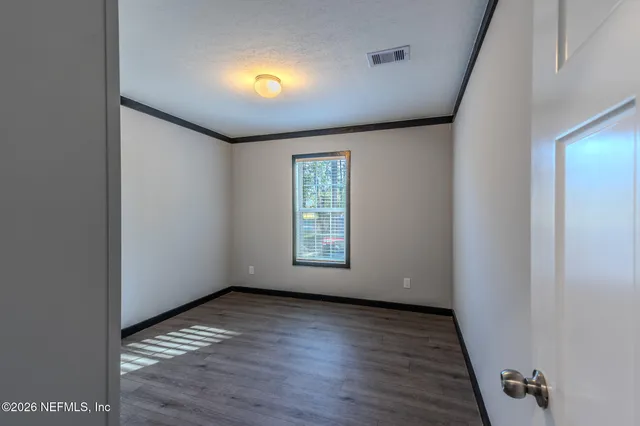 a view of empty room with wooden floor and fan