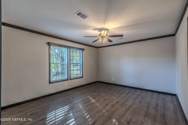 a view of an empty room with a window and wooden floor