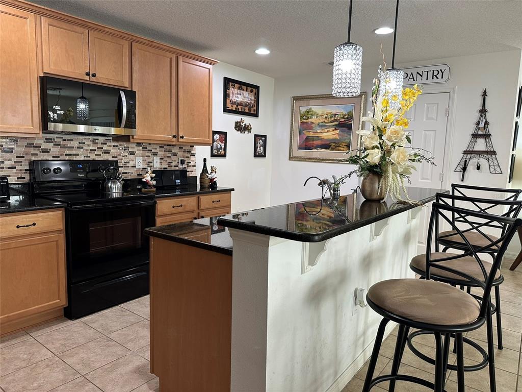 Undisclosed Address Tavares, FL 32778 - Photo 6 of 29 a kitchen with stainless steel appliances granite countertop a sink a stove a microwave a refrigerator cabinets and living room view
