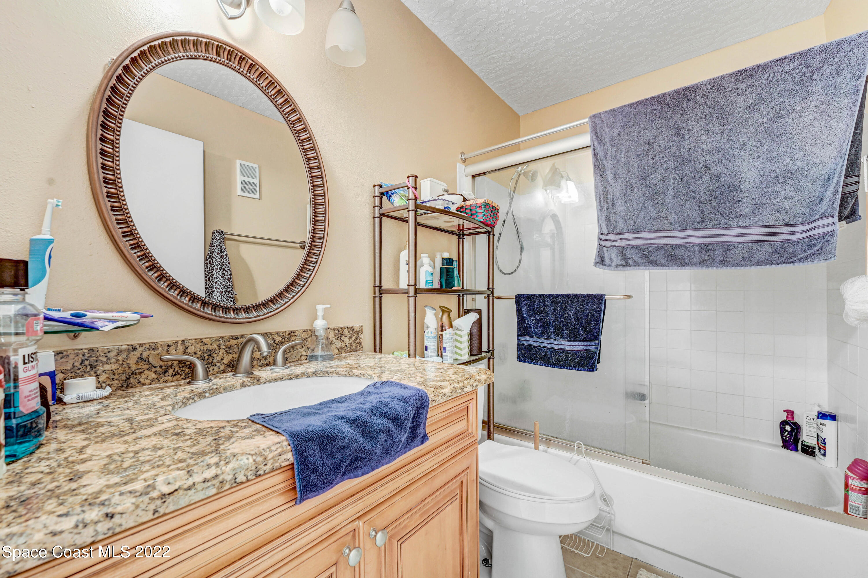 7667 North Wickham Road, Unit 107 Melbourne, FL 32940 - Photo 17 of 26 a bathroom with a toilet a sink and a mirror