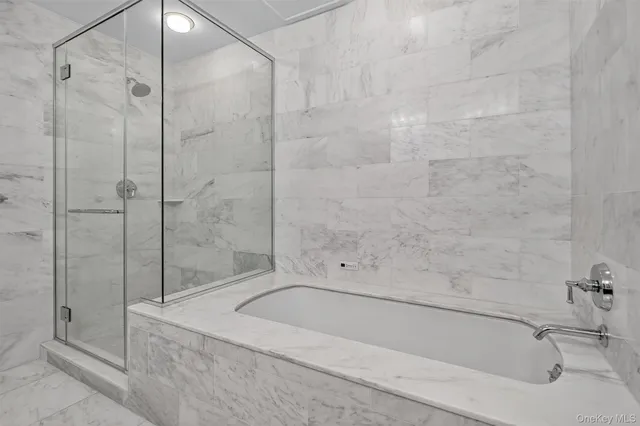 a bathroom with a tub sink double vanity granite tub shower and mirror
