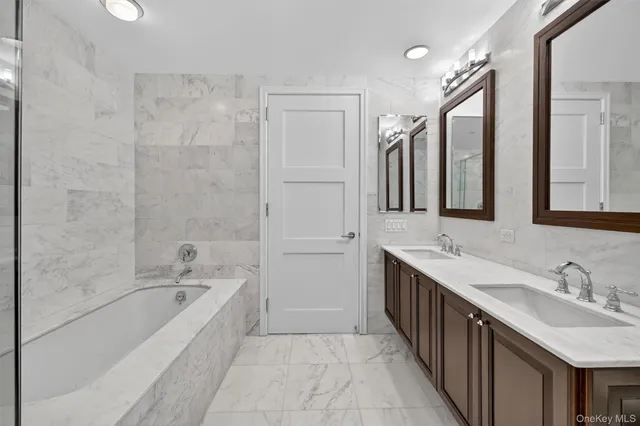 a bathroom with a sink vanity granite tub shower and a mirror