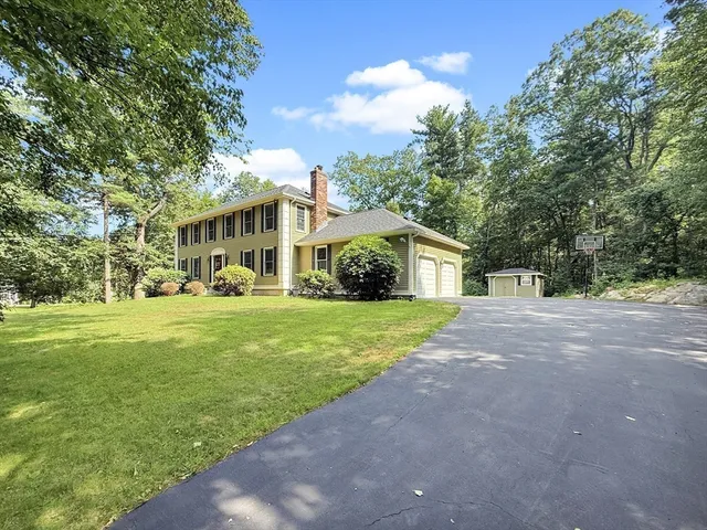 a front view of a house with a yard and trees