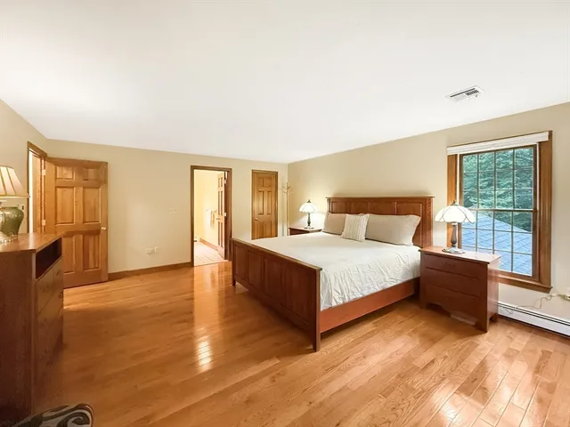 a bedroom with a large bed and wooden floor