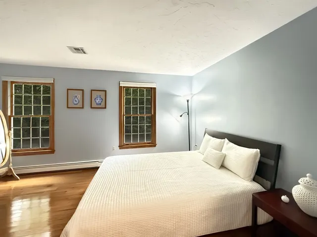 a bedroom with a large bed and wooden floor