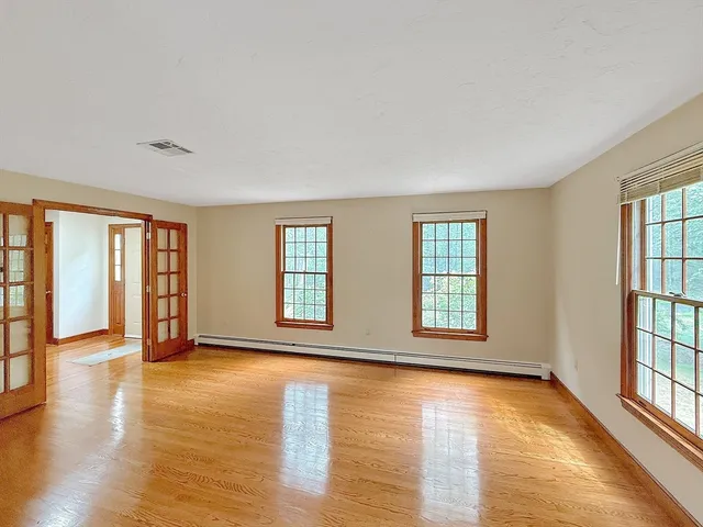 an empty room with wooden floor and windows