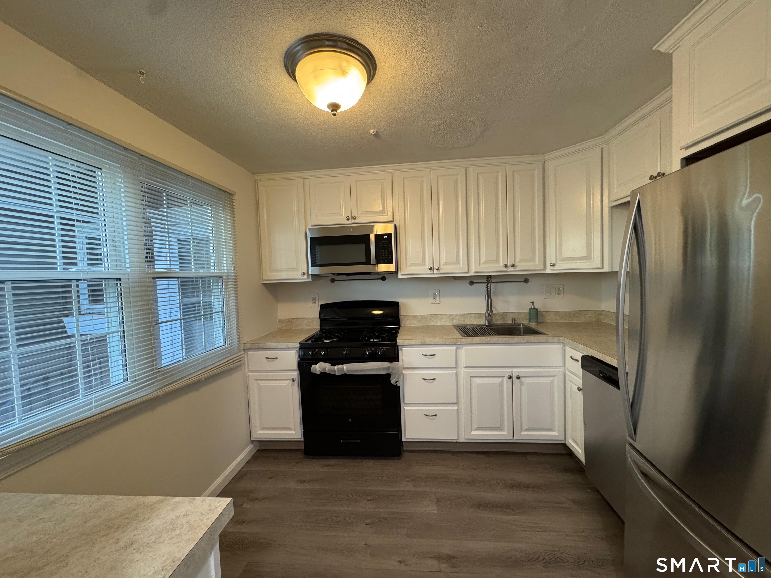 88 East Gate Lane, Unit 88 Hamden, CT 06514 - Photo 17 of 62 a kitchen with stainless steel appliances granite countertop a stove top oven a sink dishwasher a refrigerator and a microwave oven with wooden floor