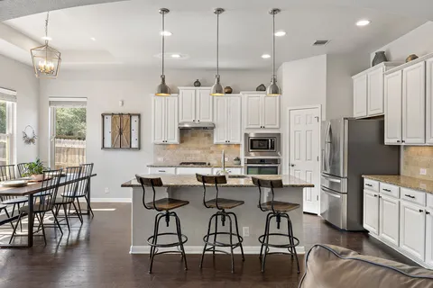 a kitchen with stainless steel appliances kitchen island granite countertop a table chairs microwave and sink