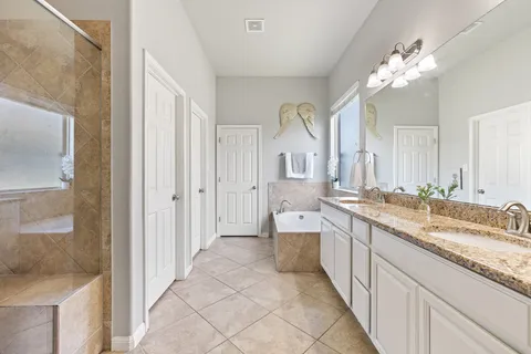 a spacious bathroom with a granite countertop sink a mirror and a shower