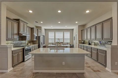 a kitchen with granite countertop a stove a sink a dining table and chairs